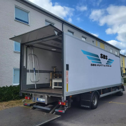 Flyttlastbil med öppet skåp och nedfälld lift för lastning.