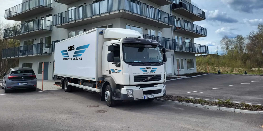 Flyttlastbil vid höghusentré för en urlastning.