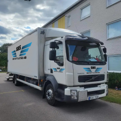 Flyttlastbil nära entrén till lägenhetshus för lättare flytthjälp.